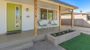 A house with a green door, two windows with lattice designs, and a covered porch with two chairs and a small table. - 14th Coronado Historic District Phoenix (Phoenix)