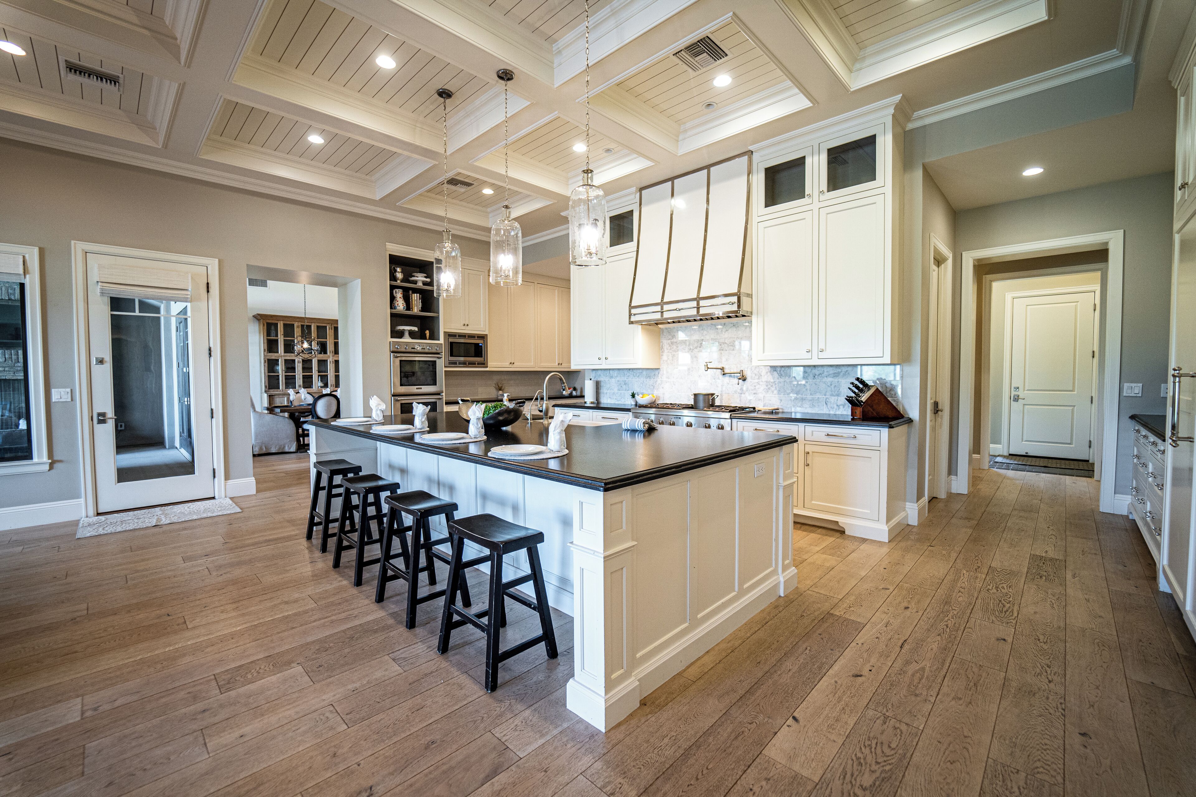 A spacious kitchen with a large island, wooden flooring, and white cabinetry.