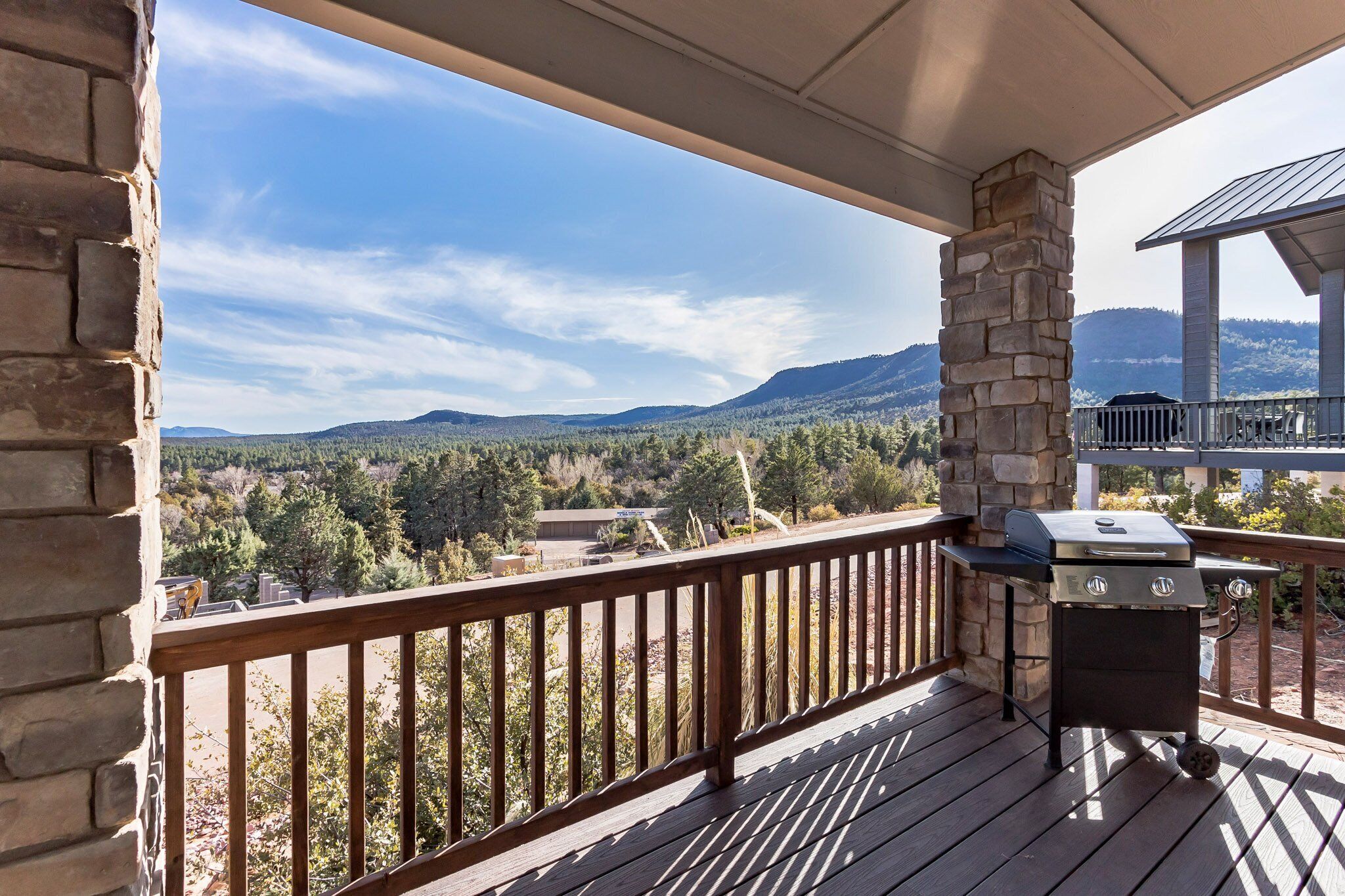 Un balcon agrémenté d’un pilier en pierre, d’un barbecue et offrant une vue sur un paysage montagneux.