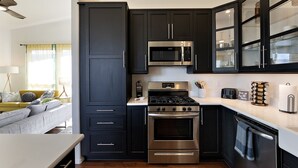 A modern kitchen with dark cabinetry, stainless steel appliances, and a built-in microwave.