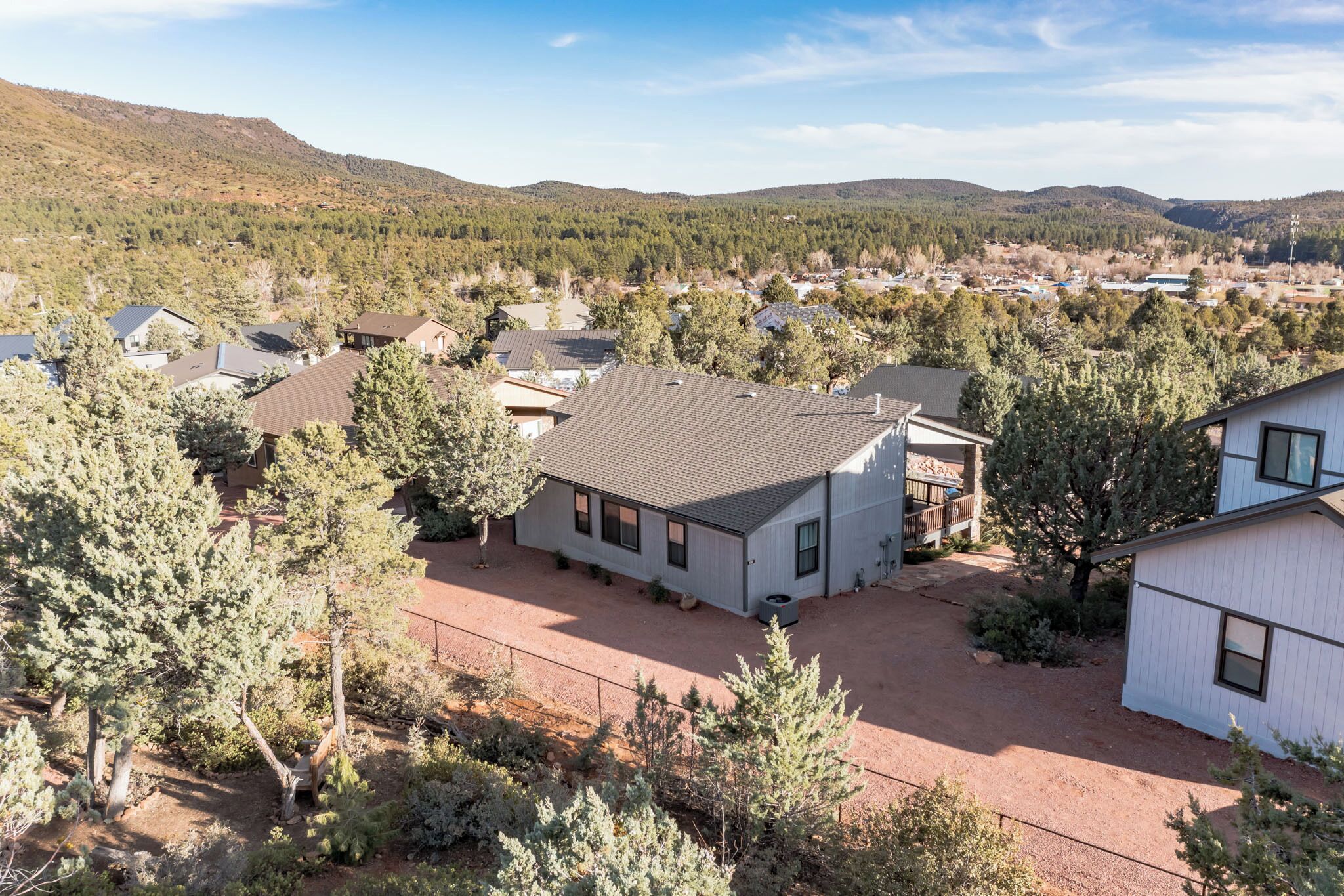 A residential area with houses, a dirt driveway, and a mountainous backdrop.