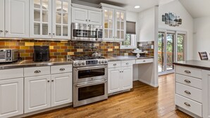A modern kitchen with white cabinets, stainless steel appliances, and a wooden floor. - Sinagua Heights Flagstaff (Flagstaff)