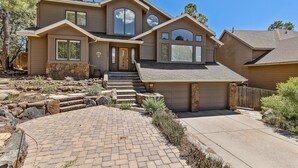 A two-story house with a front entrance, a stone staircase, and a paved driveway. - Sinagua Heights Flagstaff (Flagstaff)