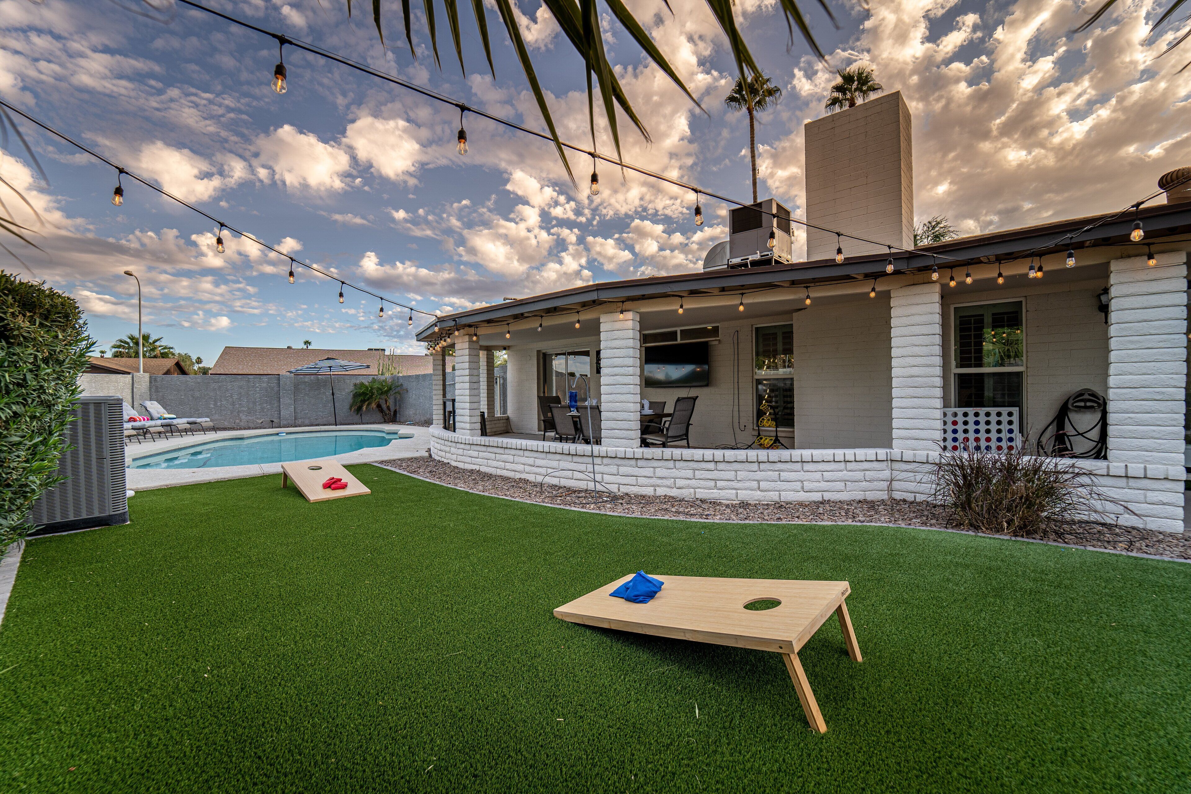 Ein Garten mit Kunstgrasanlage, einem Holztisch und einem Pool.