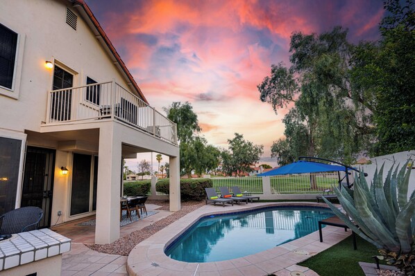 A backyard with a swimming pool, a covered patio, and a two-story house with a balcony. - 73rd Glendale (Glendale)
