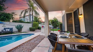 A patio with a pool, dining table, and chairs, surrounded by a garden and a house. - 73rd Glendale (Glendale)