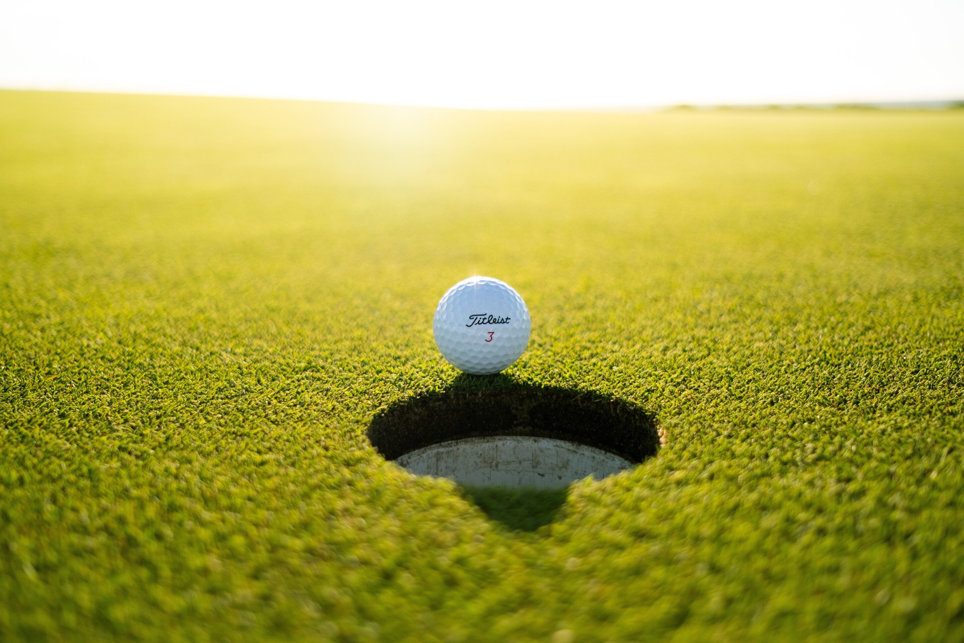 Une balle de golf sur un green, près d’un trou.
