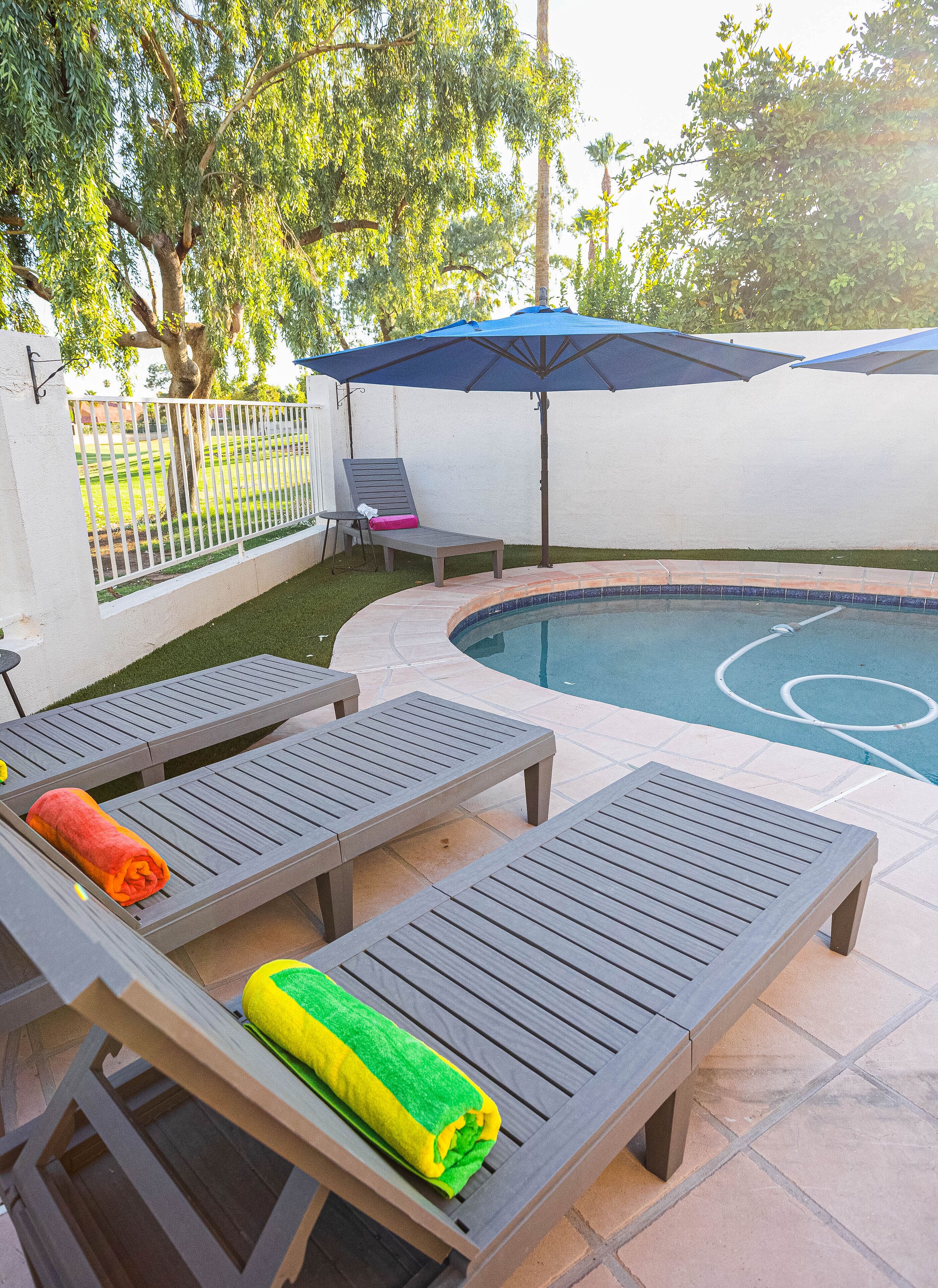 A poolside area with lounge chairs, a pool, and a covered patio.