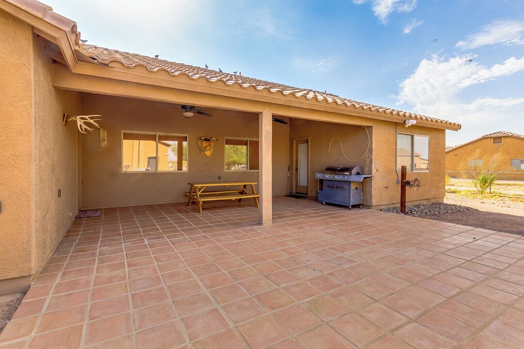 Eine überdachte Terrasse mit Picknicktisch und Grill, eine kleine Küchenzeile und Blick auf die umliegende Landschaft.