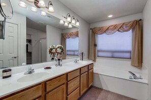 A bathroom with a double sink, vanity, mirror, and a bathtub. - Lamb Road Casa Grande (Arizona City)
