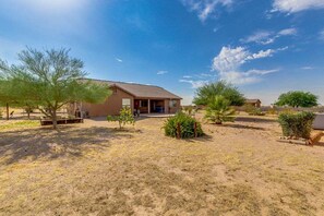 A single-story building with a flat roof and a small porch. The surrounding area is arid with sparse vegetation and a clear sky. - Lamb Road Casa Grande (Arizona City)