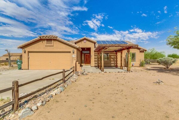 A single-story house with a garage, a covered porch, and a solar panel on the roof. - Lamb Road Casa Grande (Arizona City)