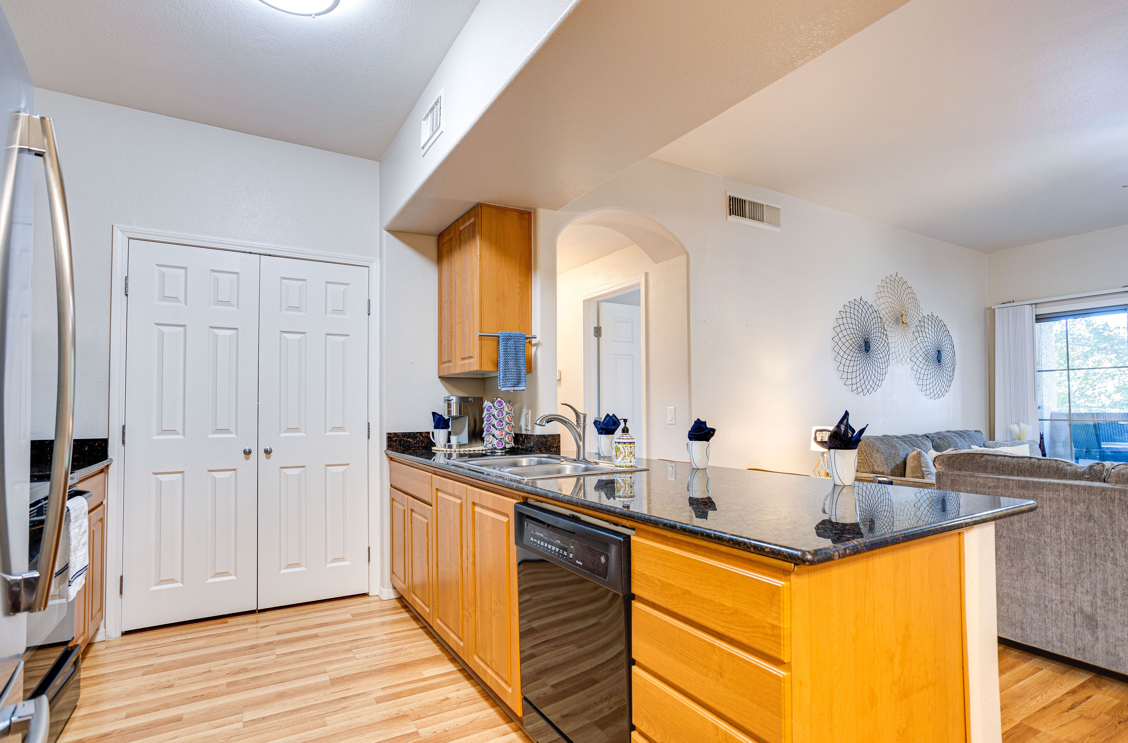 A modern kitchen with wooden cabinets, a dishwasher, and a granite countertop.