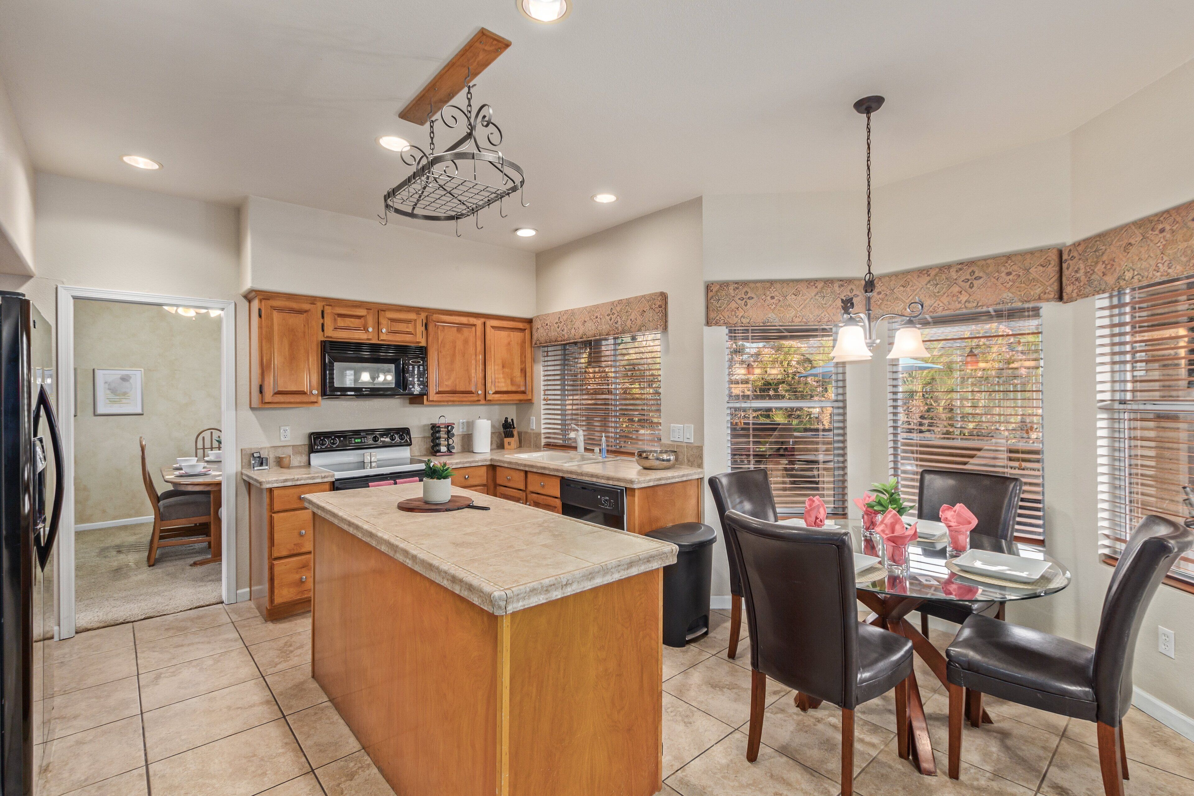 Una cocina moderna con armarios de madera, una isla central y un comedor con mesa y sillas de vidrio.