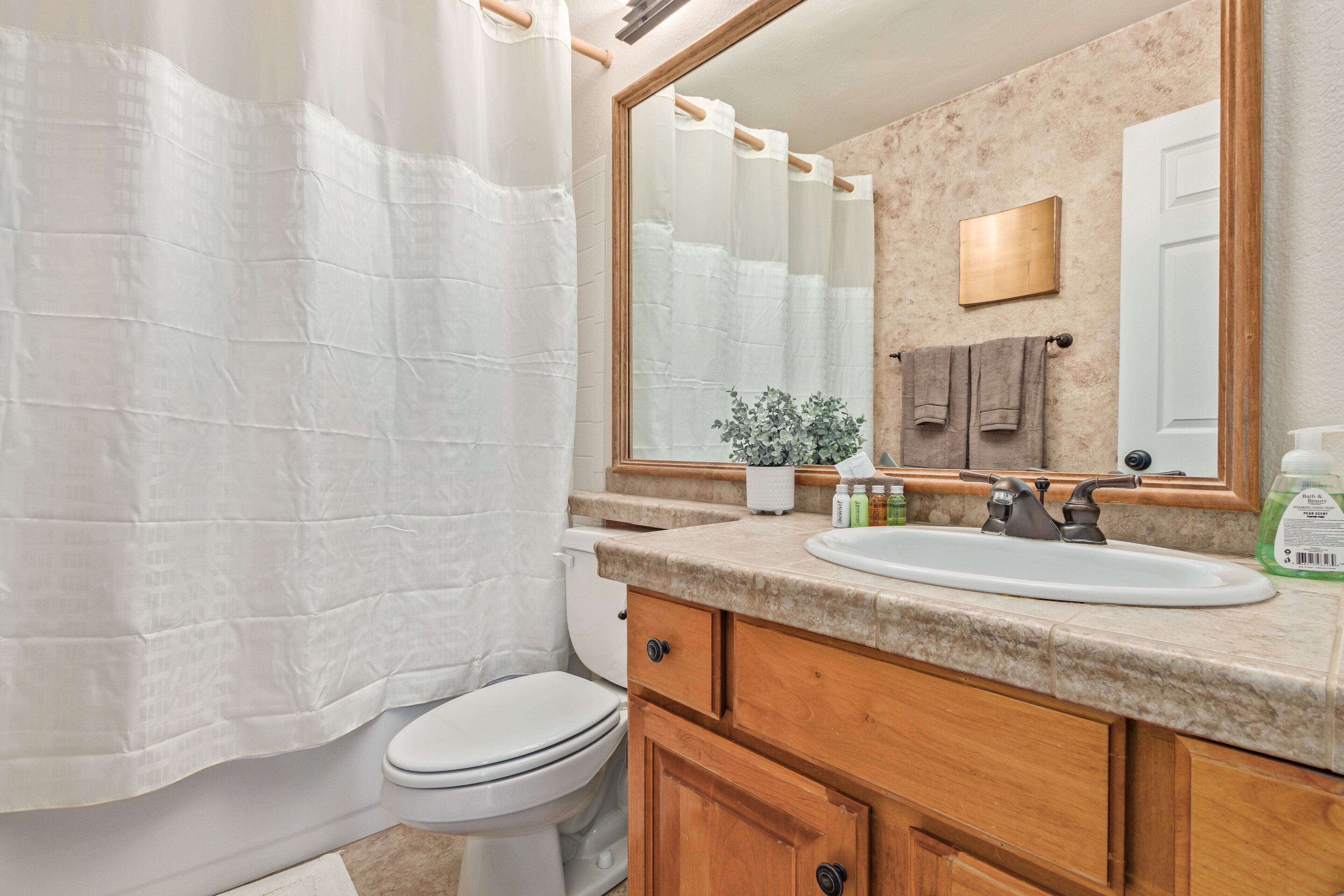 A bathroom with a white toilet, a sink with a mirror above it, and wooden cabinets.