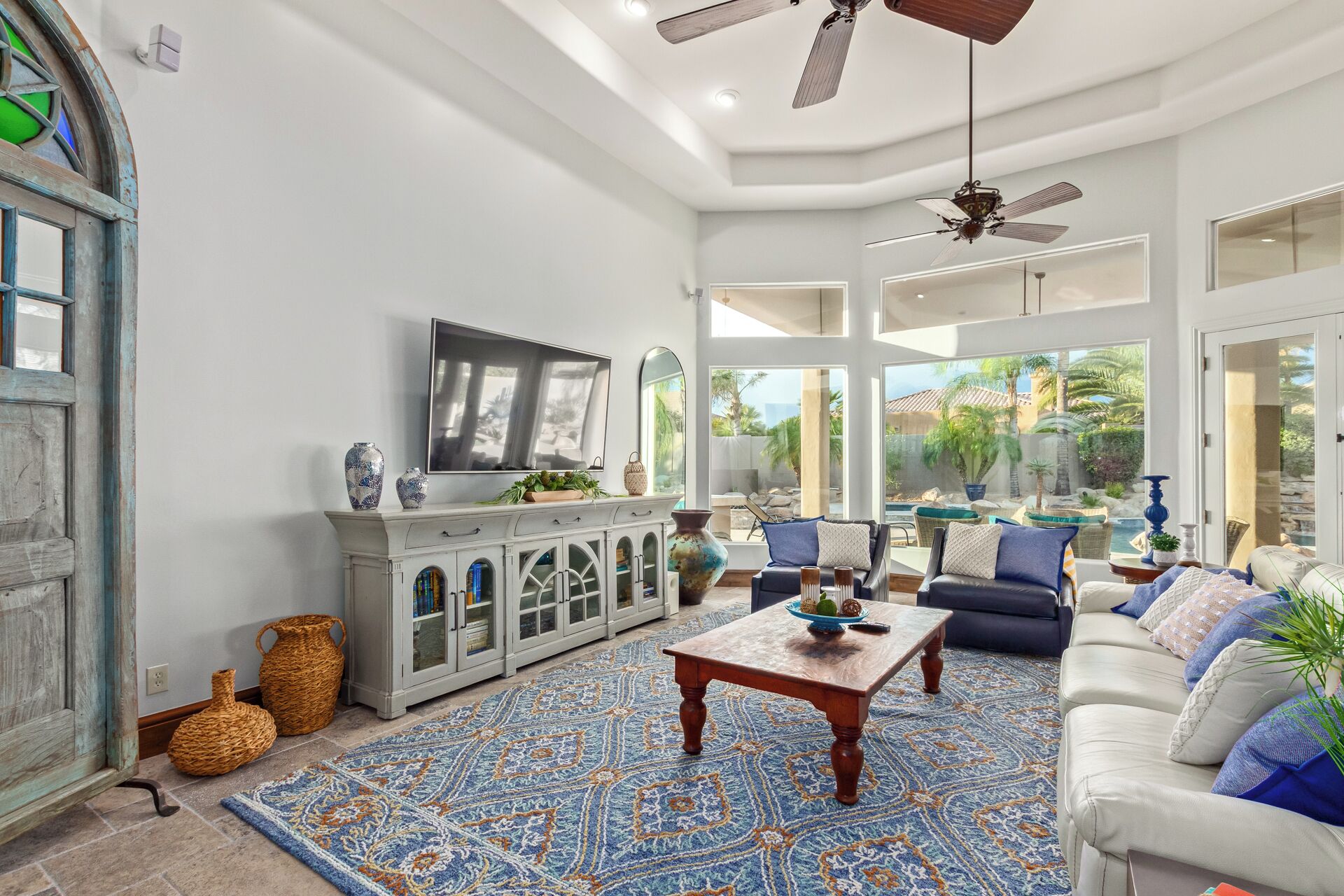 A spacious living room with a large window, a fireplace, and a ceiling fan.