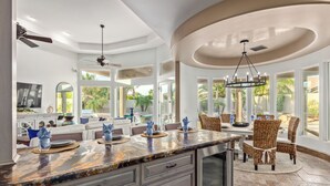 A spacious kitchen with a marble countertop, built-in cabinets, and a dining area with wicker chairs and a chandelier. - Recker #73 Mesa (Mesa)