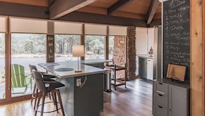 Una cocina moderna con una isla grande, pared de piedra y un menú en pizarra que enumera actividades.