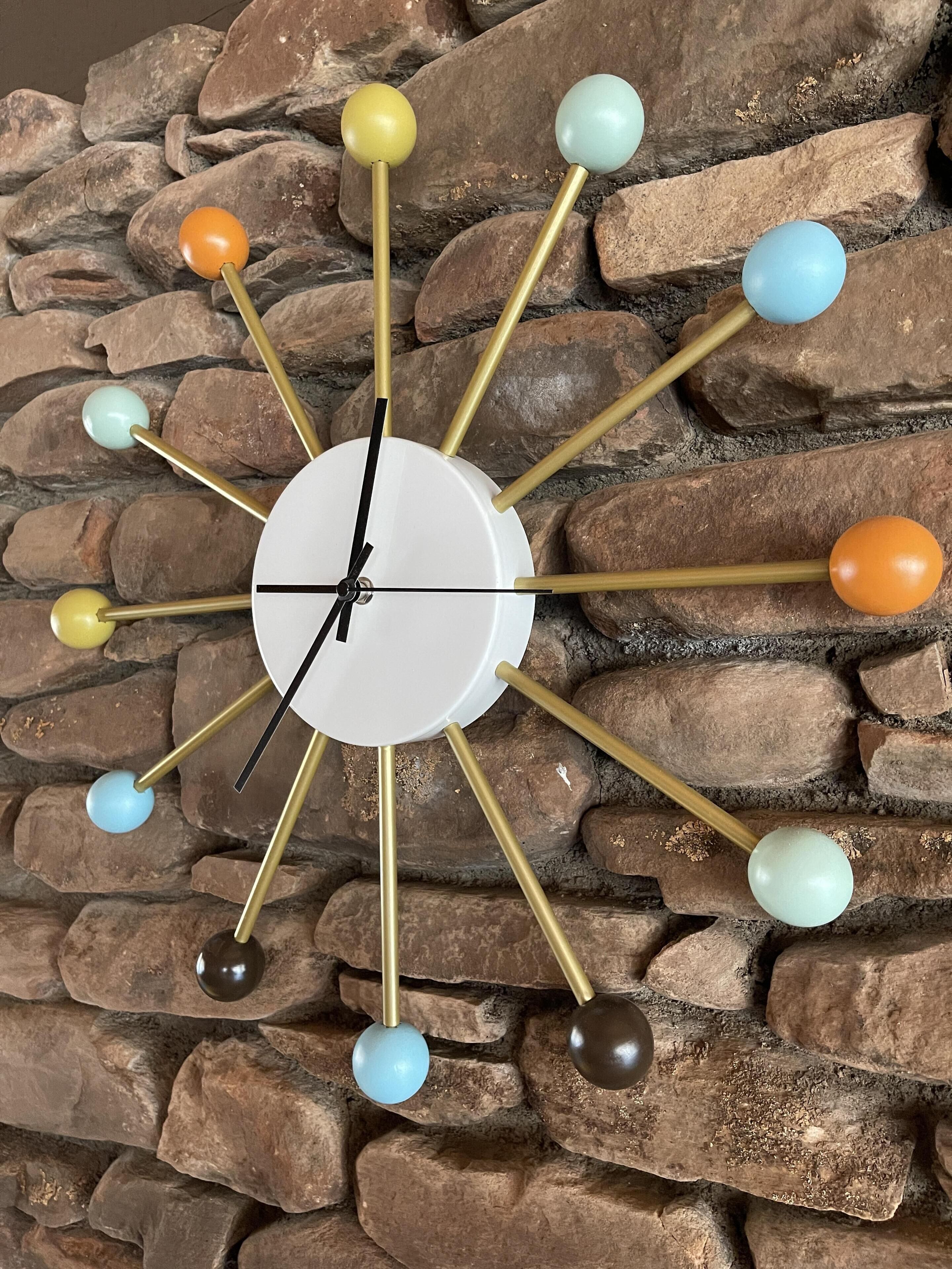 A wall clock with a modern design featuring a central white face and multiple colored hour markers.