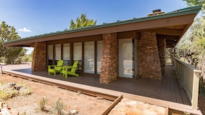 Una casa moderna con fachada de piedra, ventanas amplias y una terraza de madera.