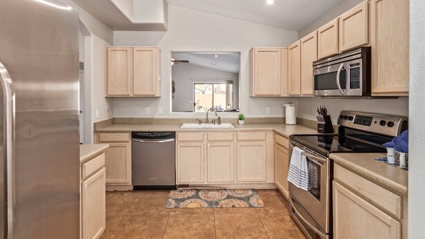 A modern kitchen with light wood cabinets, stainless steel appliances, and a central island. - Emile Zola Peoria (Peoria)