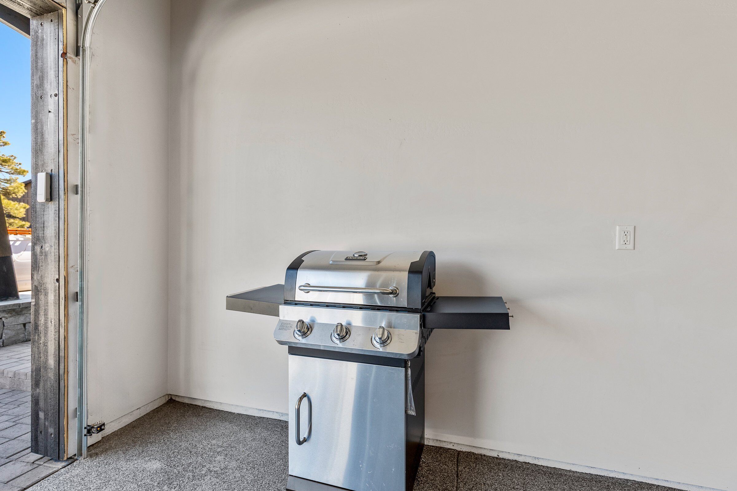 Een roestvrijstalen buitenbarbecue in een hoek van de kamer, met een witte muur en een deur.