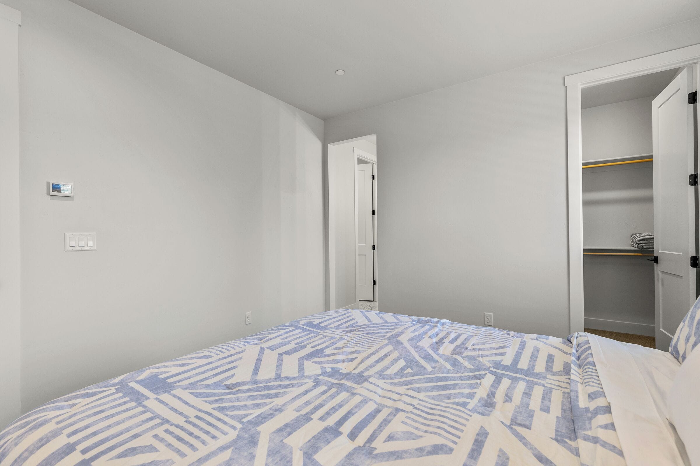 Un dormitori amb llit, armari i porta que condueix a una altra habitació.