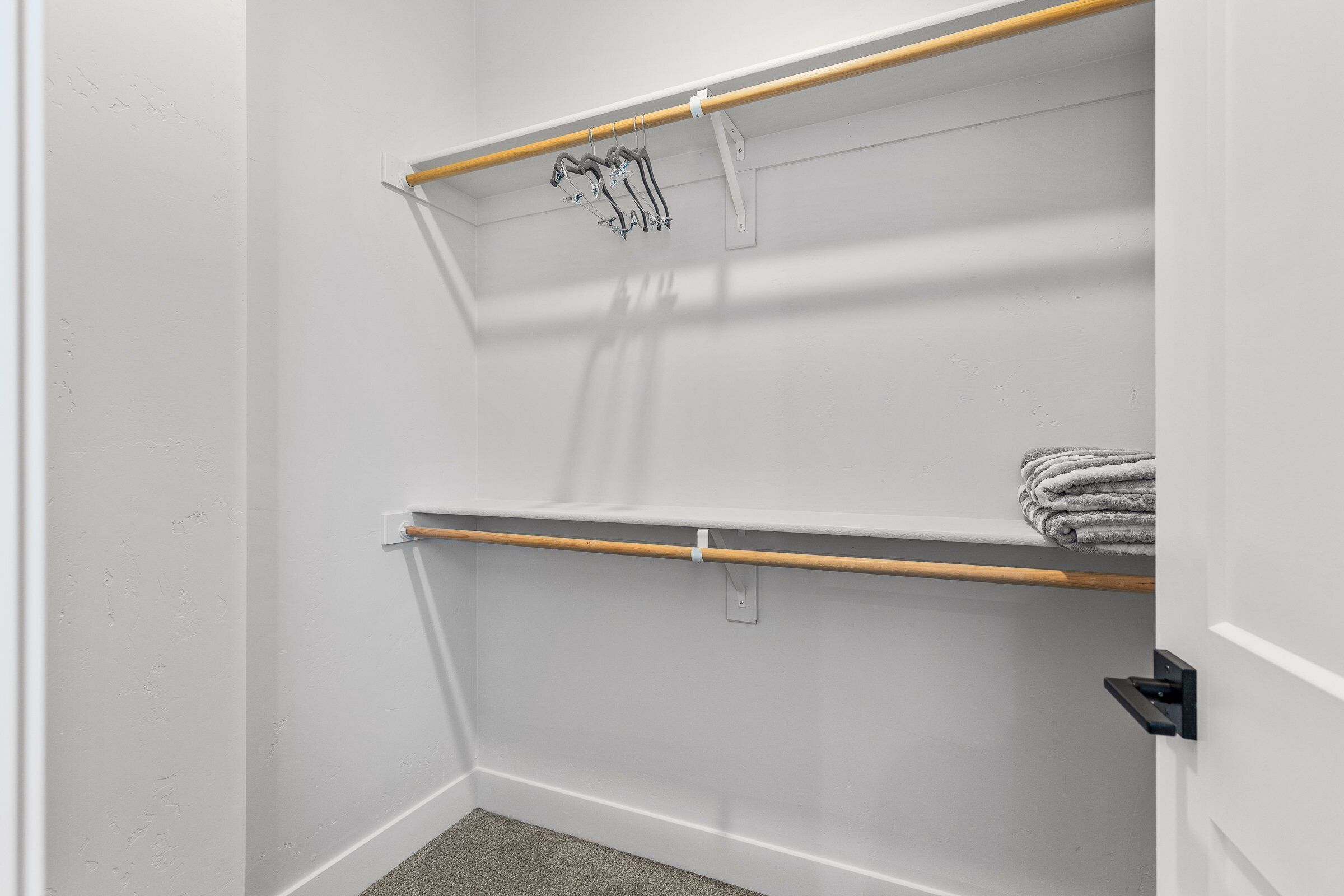 A corner of a room with white walls, a wooden door, and a towel rack with a folded towel.