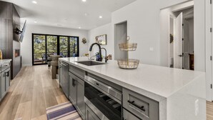 A modern kitchen with a large island, built-in appliances, and a view to the outdoors. - Cottonrose Flagstaff (Flagstaff)