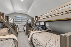 Un dormitorio con literas, una escalera y una ventana con persianas.