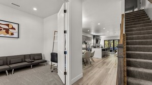 A modern interior with a grey sofa, a staircase, and a kitchen area. - Cottonrose Flagstaff (Flagstaff)