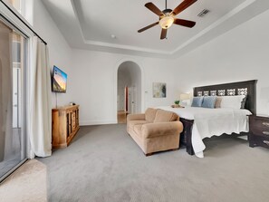A bedroom with a bed, a ceiling fan, a TV, and a wooden cabinet.