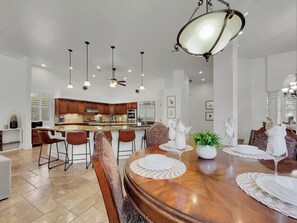 A spacious kitchen with modern appliances, a dining area with a wooden table set for four, and pendant lighting.