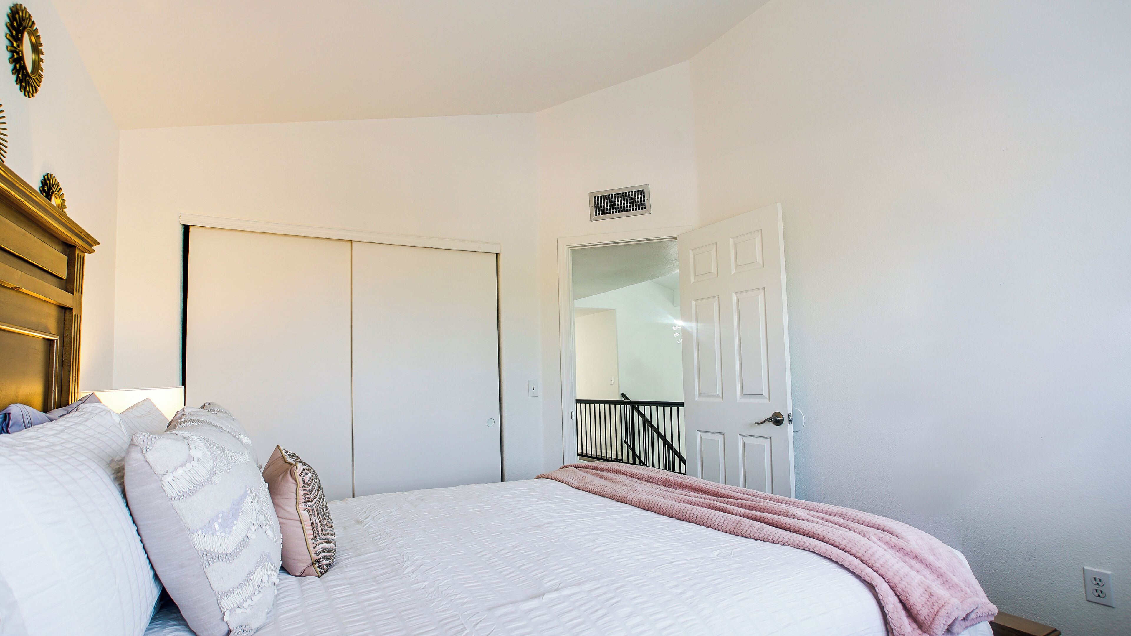A bedroom with a bed, white walls, a door, and a small window.