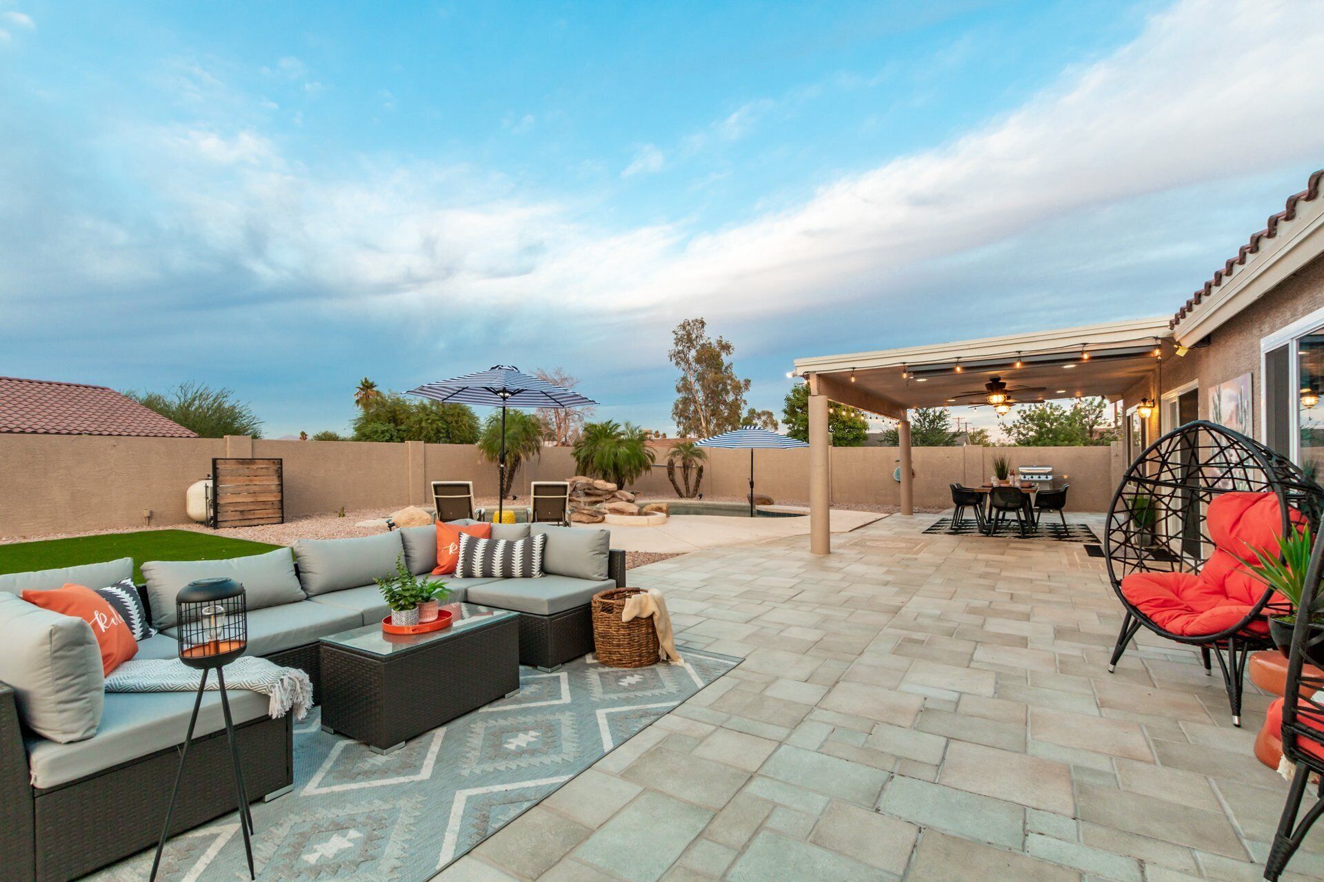 A patio with outdoor furniture, a covered dining area, and a pool.