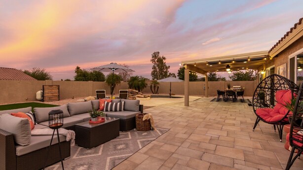 An outdoor patio with a sofa, chairs, a dining table, and a pergola with string lights. - The Golden Cactus Phoenix (Phoenix)