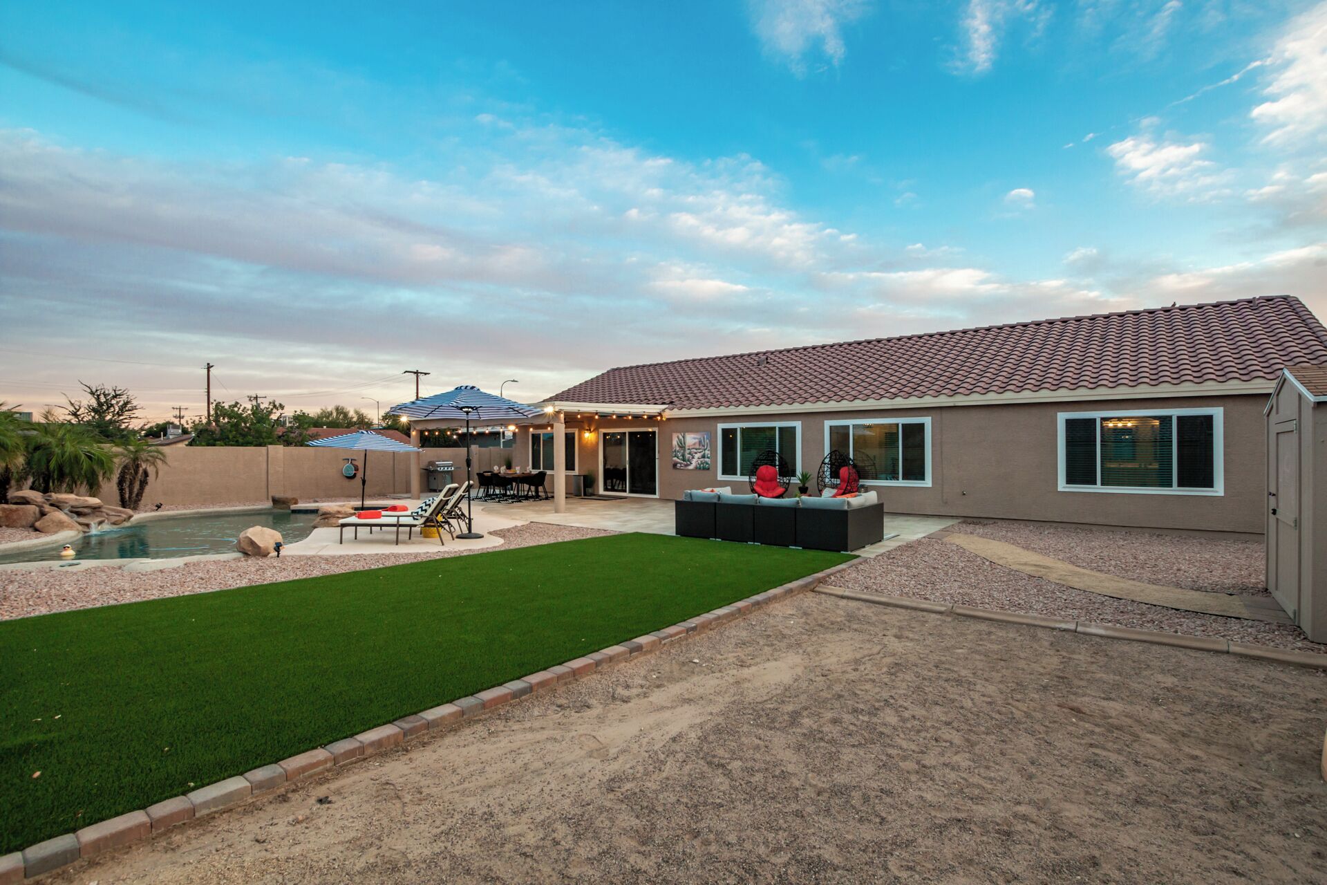 A residential property with a swimming pool, a patio with outdoor furniture, and a well-maintained lawn.