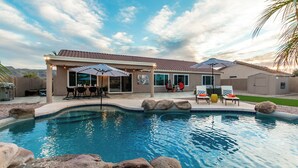 A residential pool area with a covered patio, outdoor seating, and a landscaped backyard. - The Golden Cactus Phoenix (Phoenix)