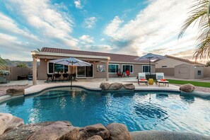 A residential pool area with a covered patio, outdoor seating, and a landscaped backyard. - The Golden Cactus Phoenix (Phoenix)
