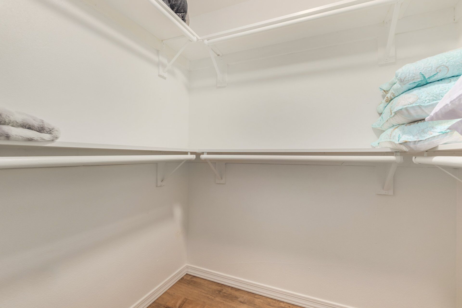 A corner of a room with white walls, a wooden floor, and a white ceiling.