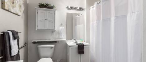 A bathroom with a toilet, sink, cabinet, and shower curtain.