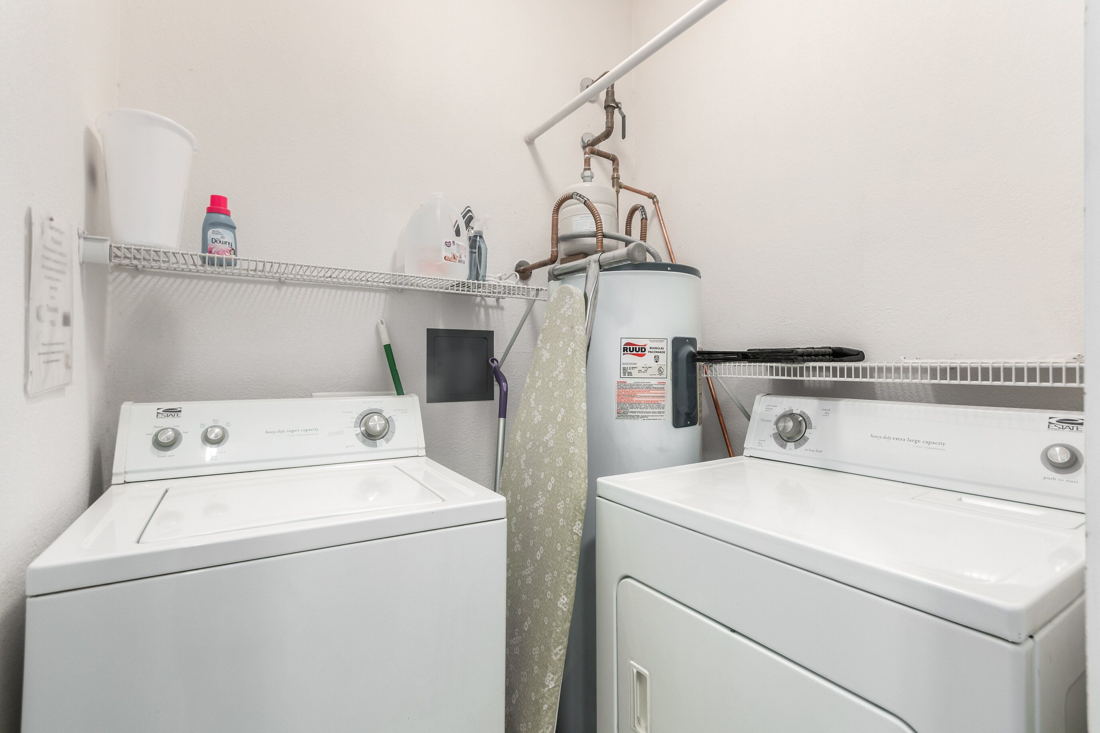 A laundry area with two front-loading washing machines, a utility sink, and a water heater.