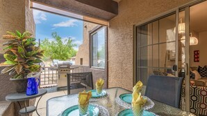 An outdoor dining area with a table set for four, surrounded by chairs, and a potted plant to the left. - Southern #1064 Mesa (Mesa)
