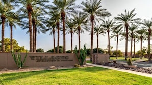 A sign for Villages at Rancho Mirage, surrounded by palm trees and a well-maintained lawn.