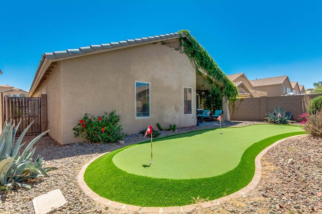 A residential property with a well-maintained lawn, a patio area, and a house with a sloped roof.