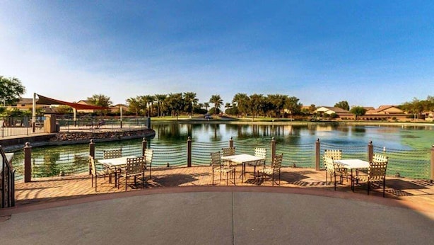 A lakeside patio with outdoor seating and a view of a calm lake.
