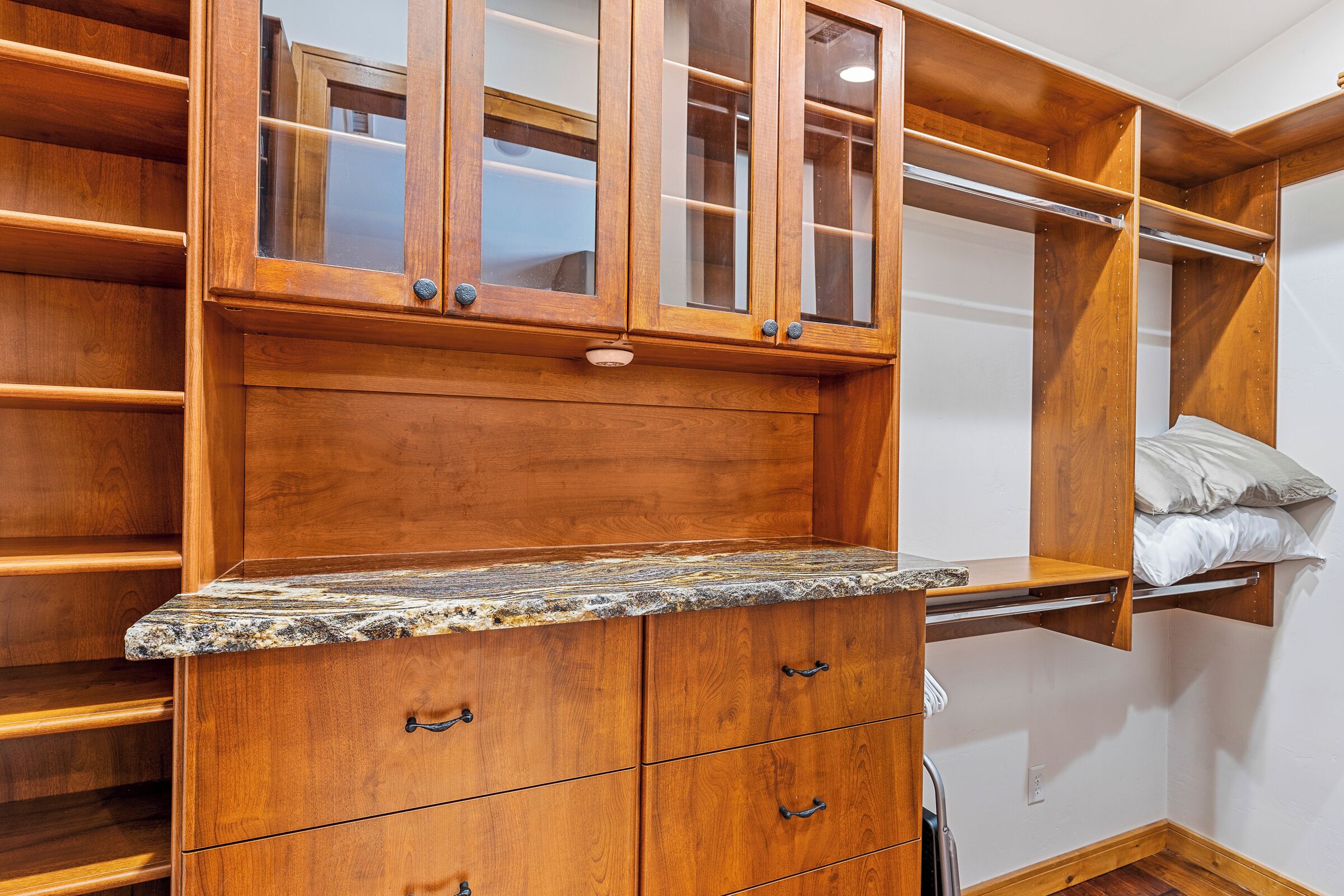 A wooden closet with open shelves, drawers, and a countertop.