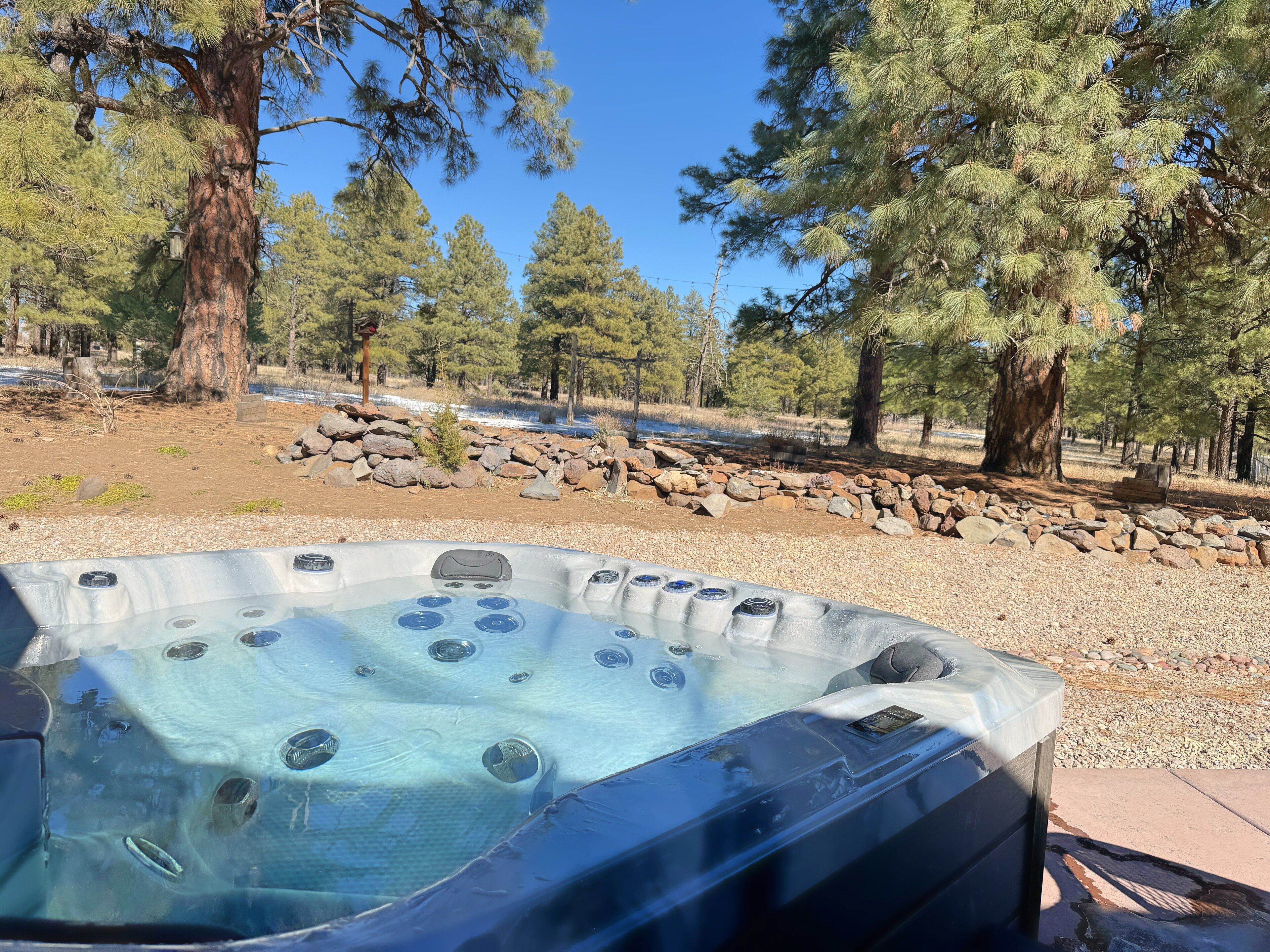 A hot tub in a natural setting with trees and rocks.