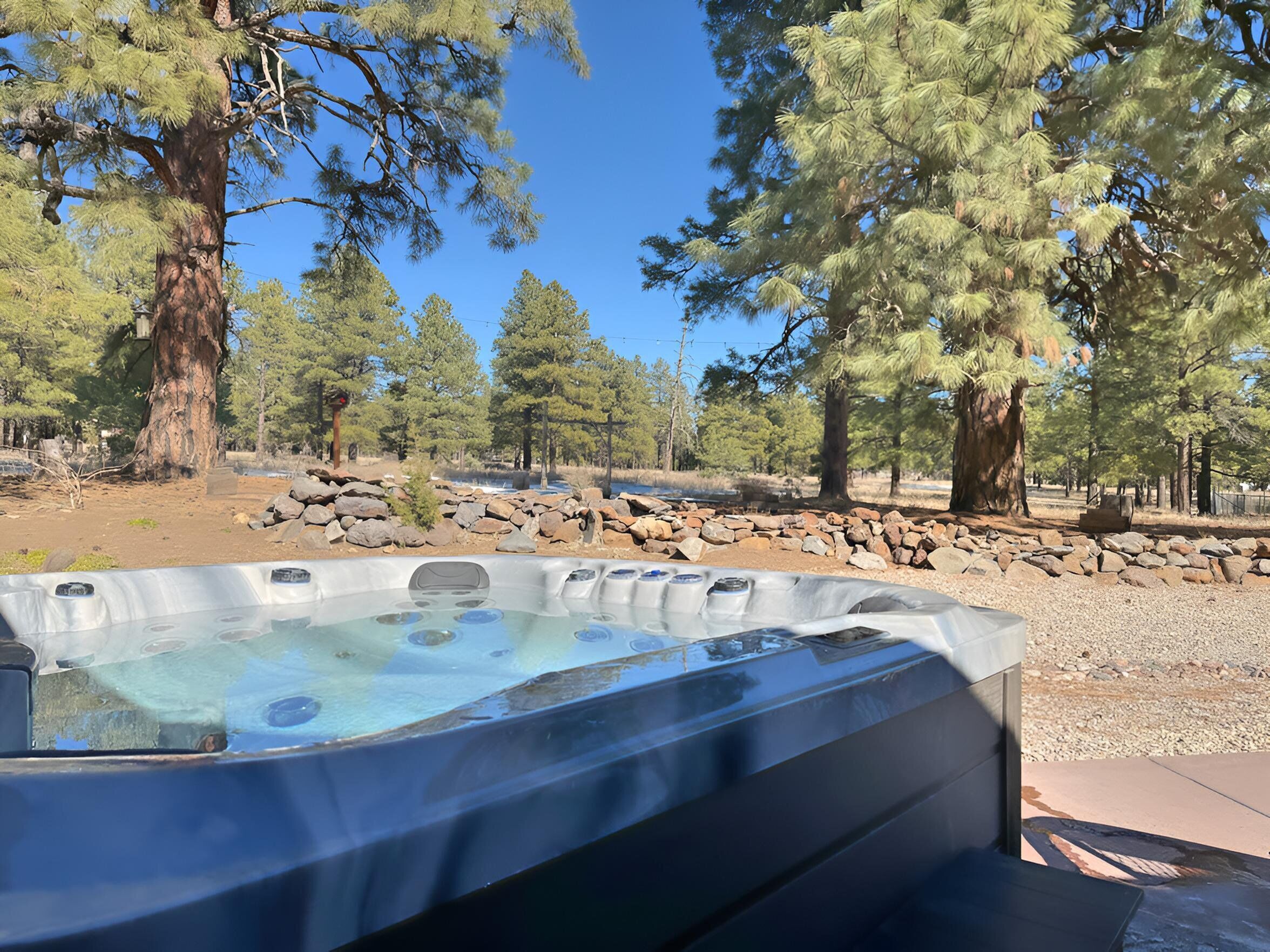 A hot tub in a natural setting with trees and rocks.