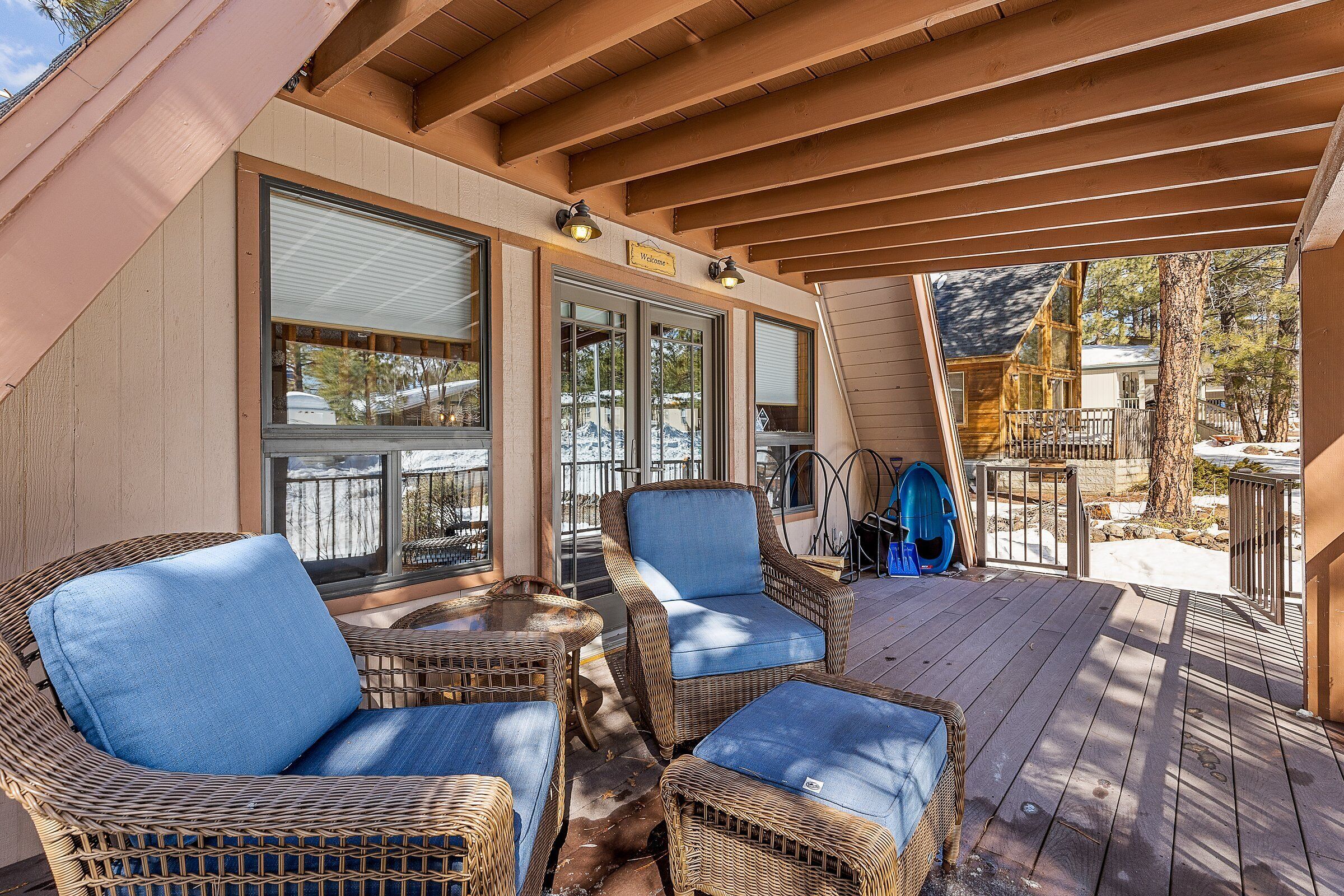 A covered outdoor seating area with wicker furniture and a wooden deck.